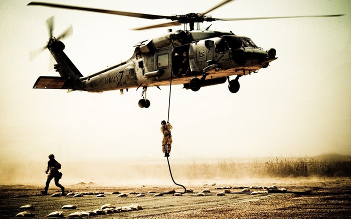 US Navy helicopter performing a rope descent in a desert