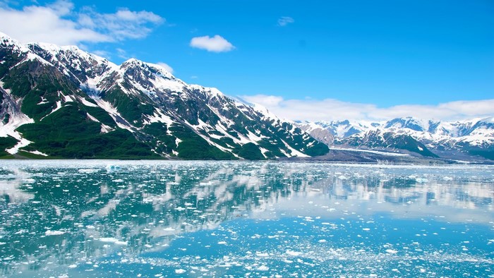 Snow-capped mountains reflected in a glacial lake with ice floes