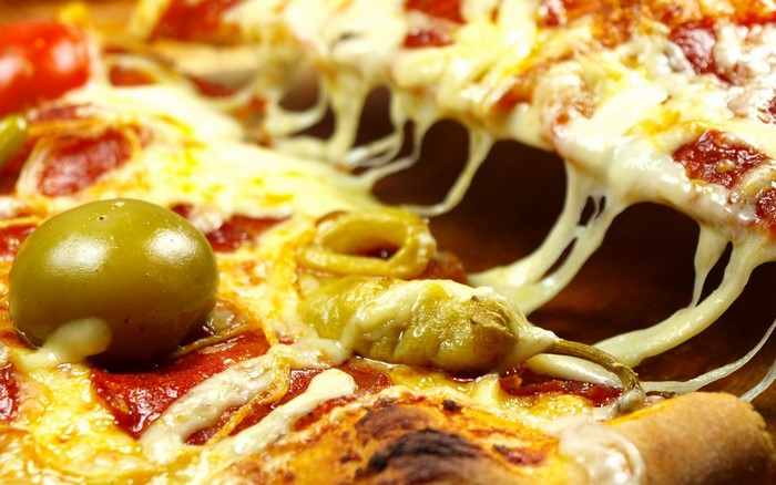 Close-up of a cheesy pepperoni pizza with olives and peppers