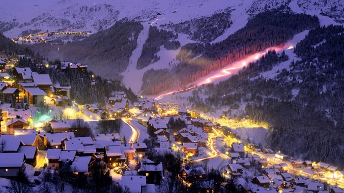 Snowy mountain village at night with ski slopes