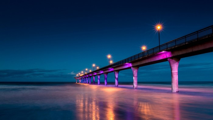 Pier with purple lights over the ocean at night