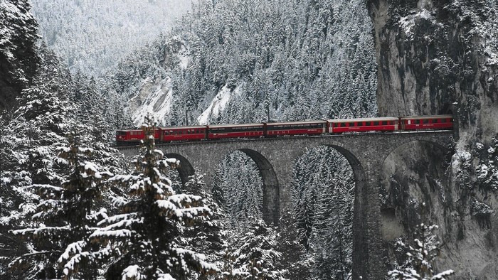 Red train on a snowy viaduct in the Swiss Alps