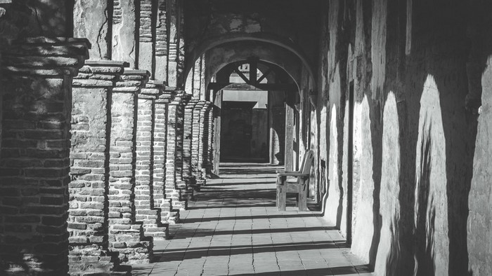 Monochrome photograph of an ancient arched hallway with columns