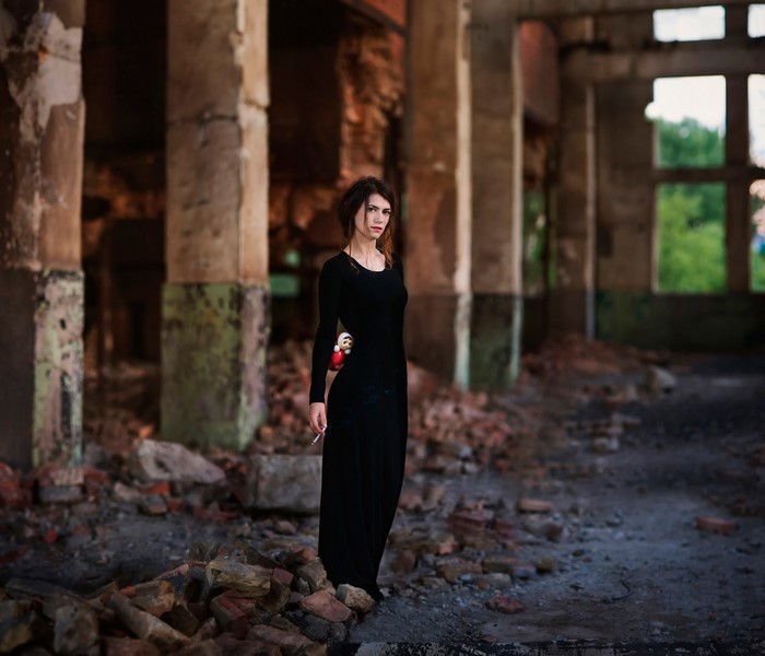 Woman in black dress holding cigarette in abandoned building