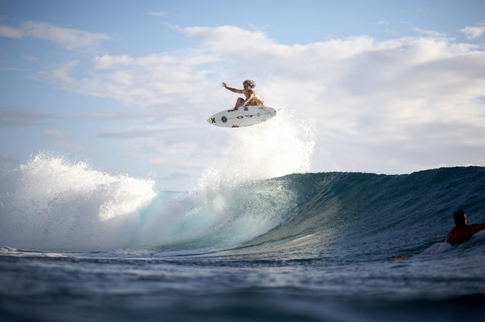 Surfer performing an aerial maneuver over a wave