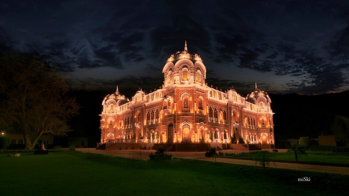 Illuminated building at night with dark clouds