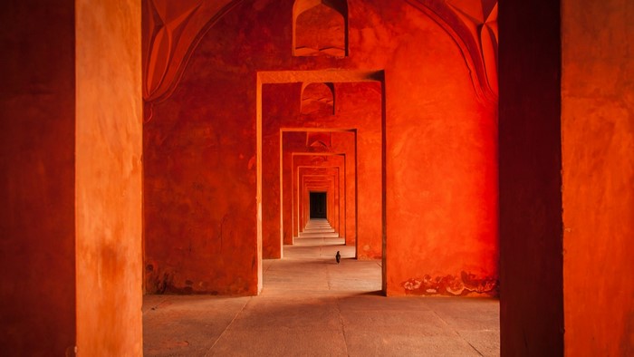 Red ancient corridor with arches and a bird