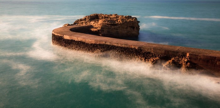 Curved breakwater and rock formation in the sea