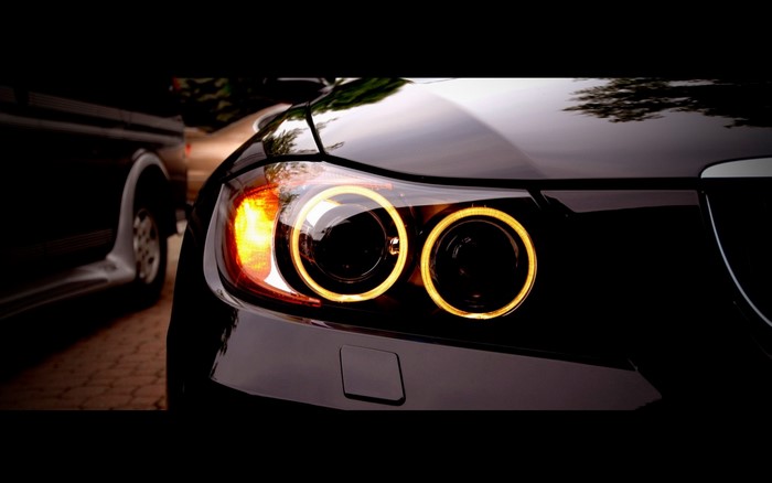 Close-up of a black BMW E90 headlight with angel eyes