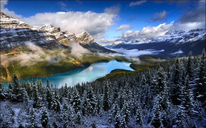 Turquoise lake surrounded by snow-covered pine trees and mountains