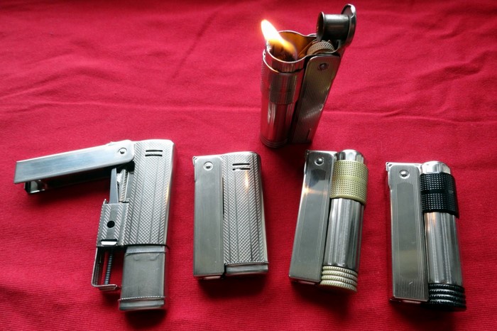 Collection of vintage lighters on a red surface