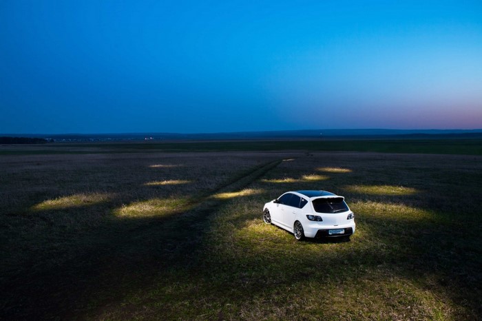 White car parked in a field at dusk