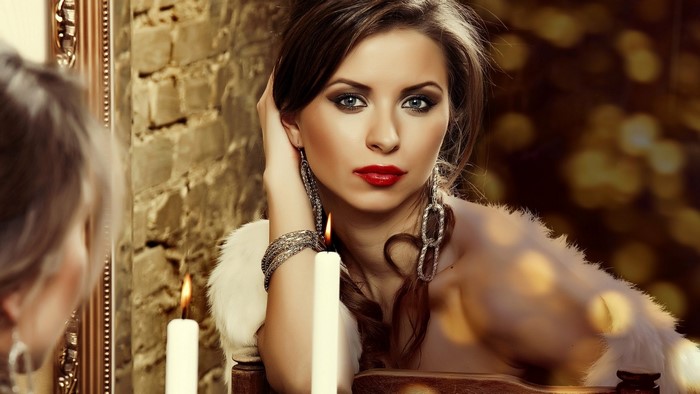 Woman with red lipstick and jewelry in front of a mirror
