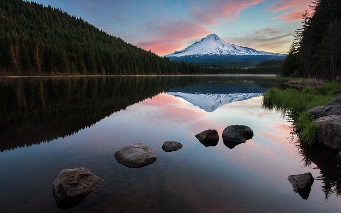 Snowy mountain reflected in a calm lake at sunrise