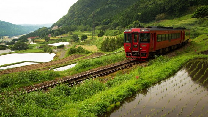 Red train on tracks through Japanese rice terraces