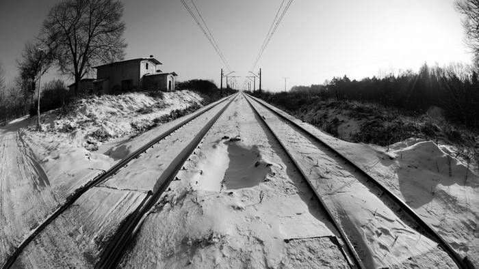 Snowy railway tracks with a building and trees