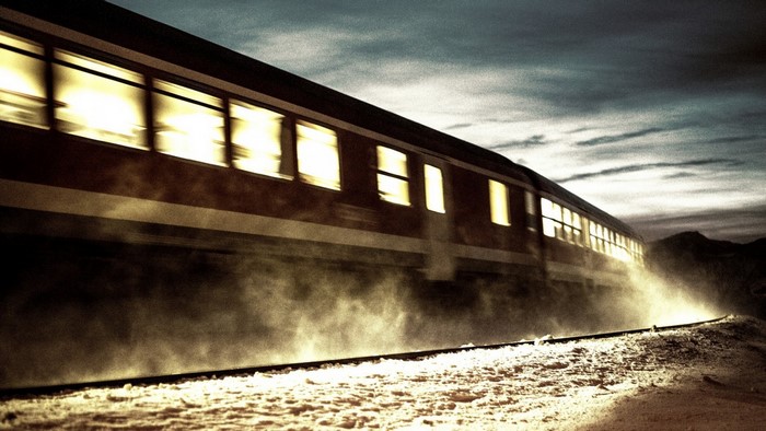 Train moving on tracks at night with illuminated windows
