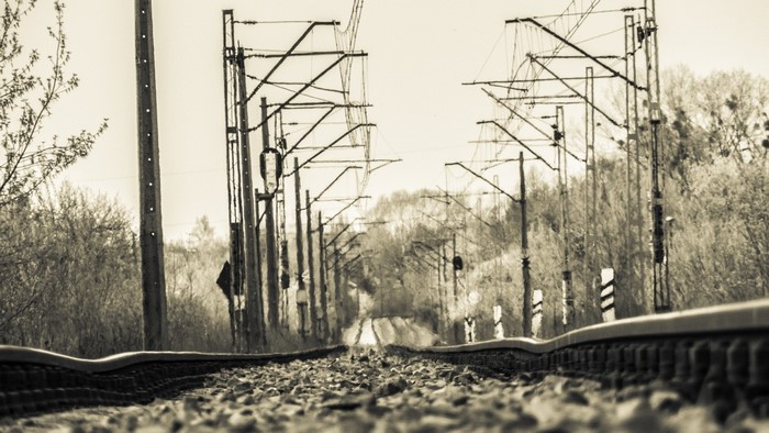 Monochrome railway tracks with overhead power lines