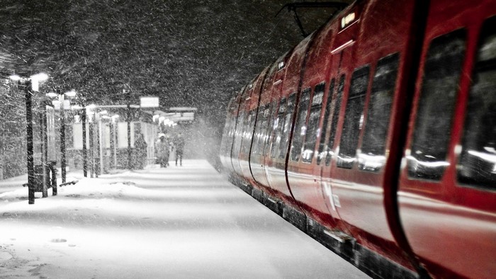 Red train at a snowy train station at night
