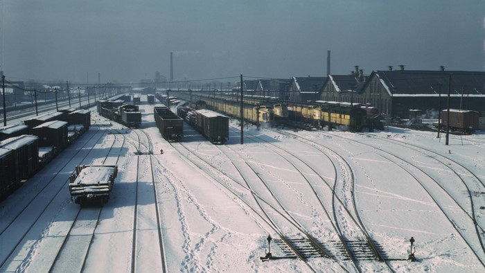 Snowy train yard with freight trains and buildings