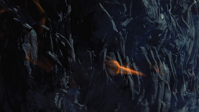 Close-up of burning dark material with orange flames