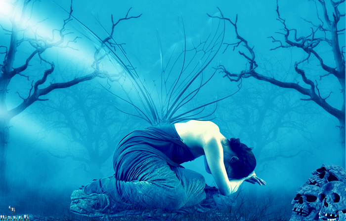 Woman kneeling in a blue, eerie forest with skulls