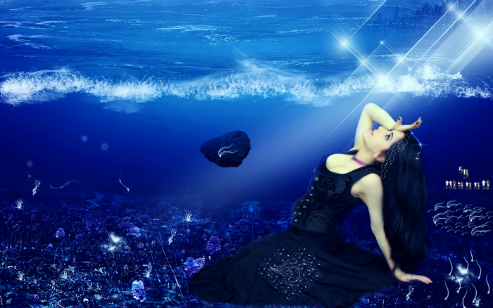 Woman in black dress underwater with light beams