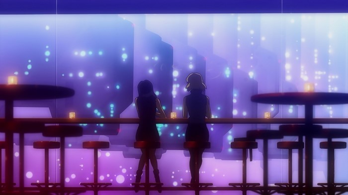 Two women at a bar overlooking a city at night
