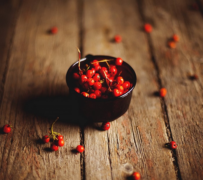 Red berries in a bowl on a wooden surface
