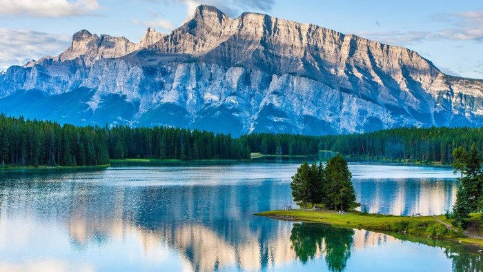 Mountain range reflected in a calm lake with pine forest