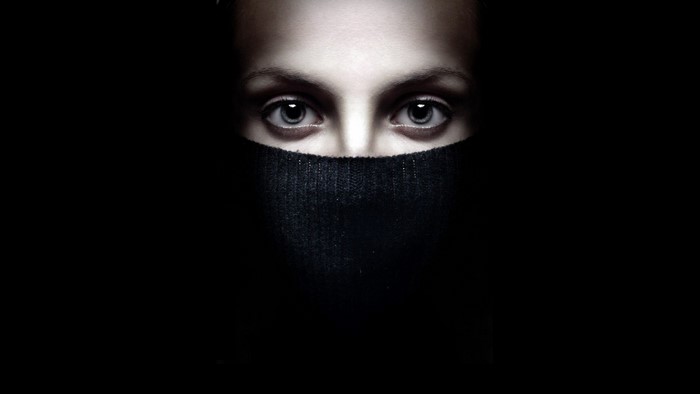 Close up of a woman's eyes and mouth covered by a black sweater