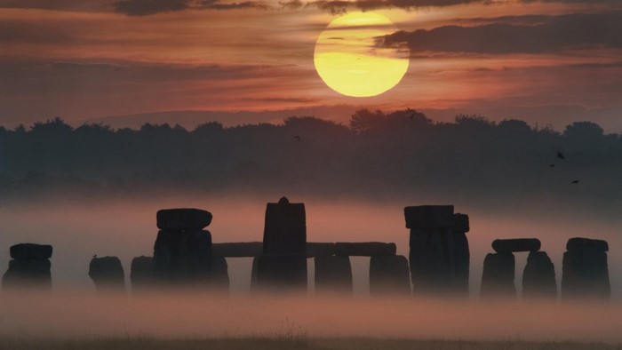 Stonehenge at sunrise with mist and sun
