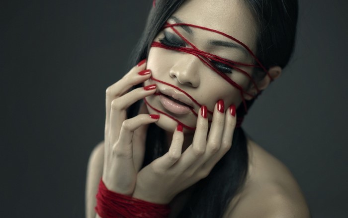 Woman with red yarn on face and hands