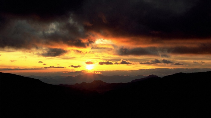 Sunset over mountains with dark clouds