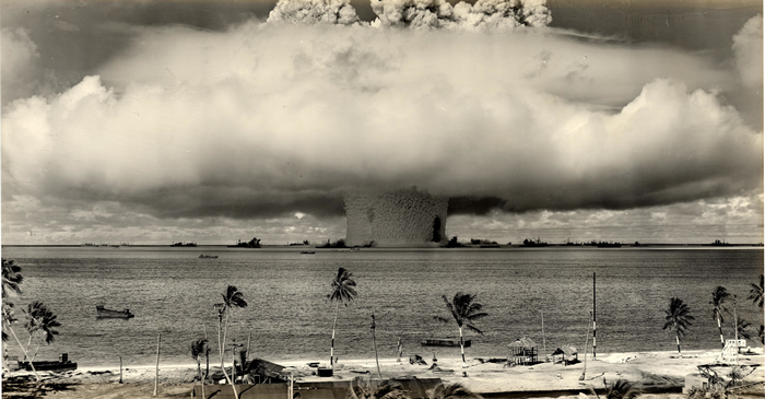 Nuclear explosion over the ocean with ships and palm trees