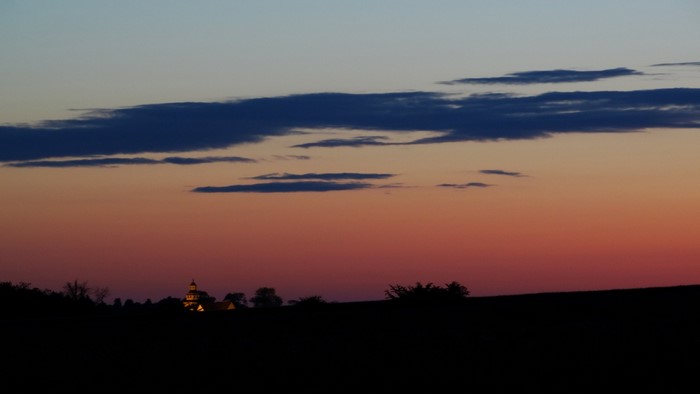 Silhouette of a church and trees against a sunset sky