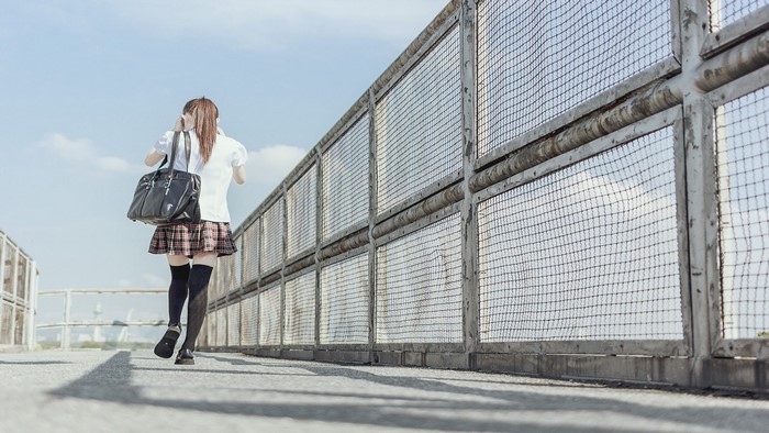 Schoolgirl with bag walking on a walkway