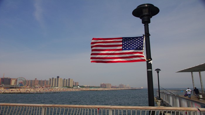 American flag on a pier with Coney Island in the background