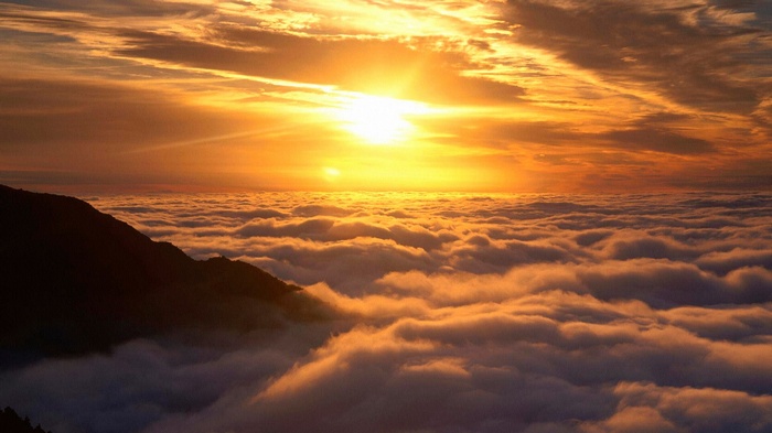 Sunset over clouds with mountain peak
