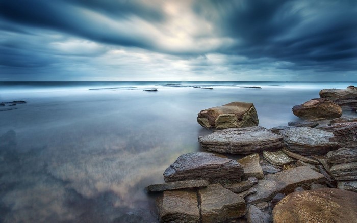 Long exposure of rocky coast under dramatic clouds