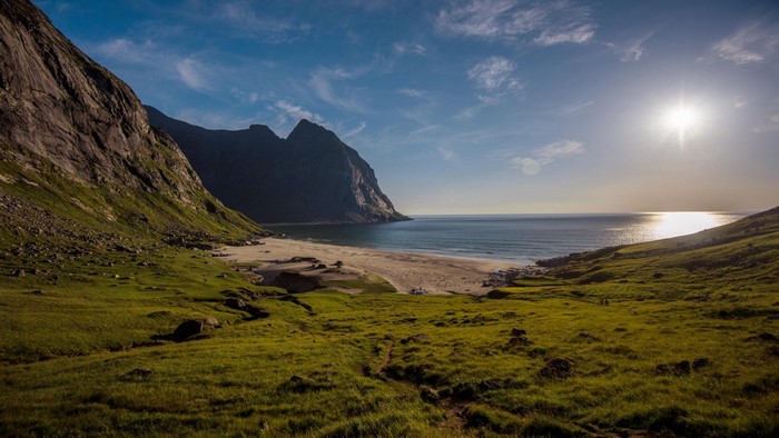 Mountainous coast with a beach and ocean under a sunny sky