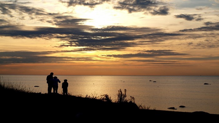 Silhouettes of people watching the sunset over the sea