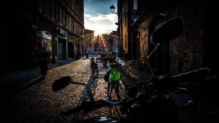 Motorcycle parked on a cobblestone street at sunset