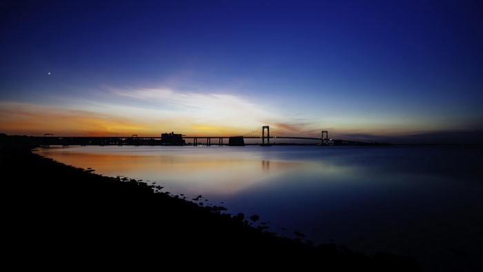 Bridge over water at dusk with moon