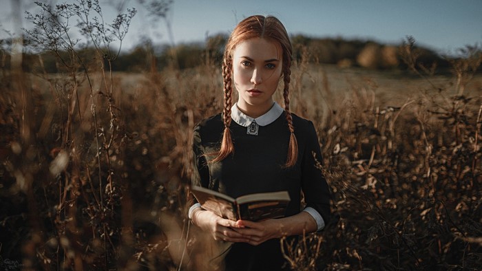 Woman with braids holding a book in a field