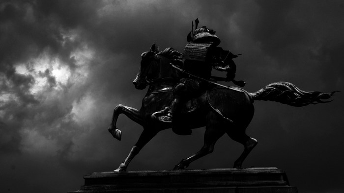 Samurai warrior statue on horseback against stormy sky