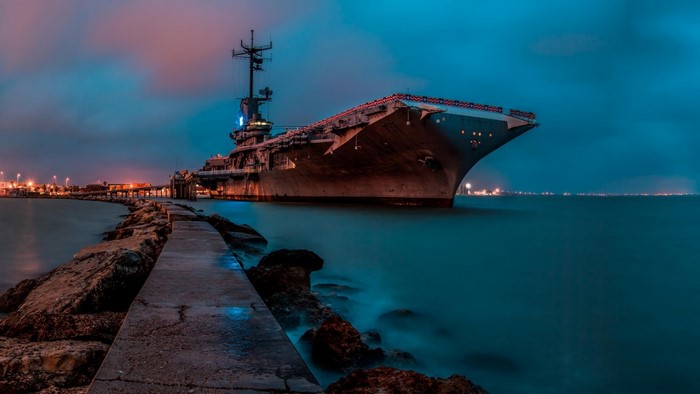 USS Lexington aircraft carrier at dusk with pier