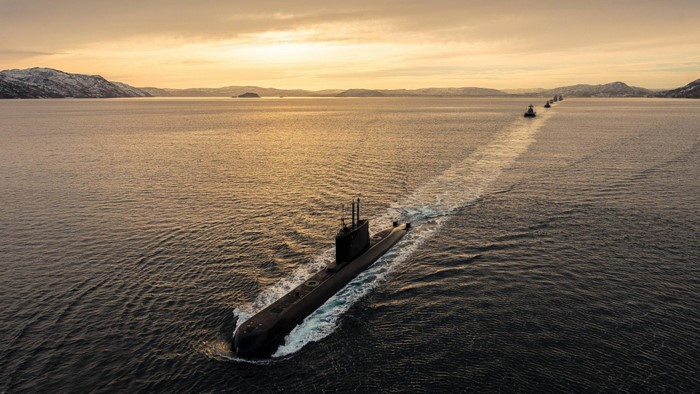Submarine and ships sailing in the ocean at sunset