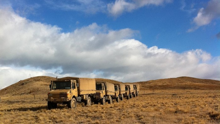 Military Unimog trucks lined up in a rural landscape