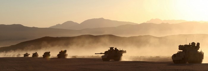 Military tanks in a desert at sunrise
